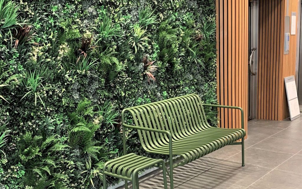 Artificial living wall behind green bench