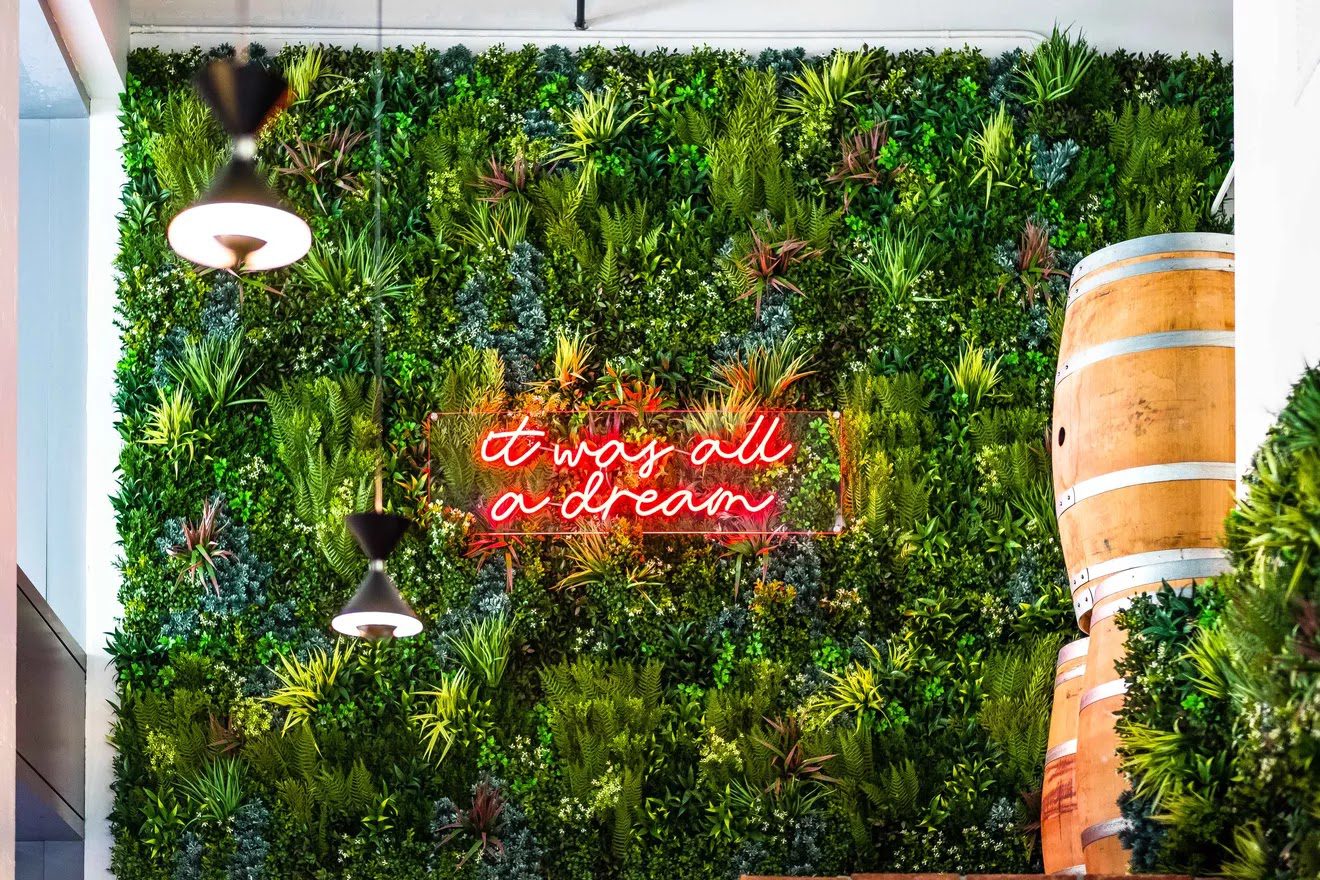 an artificial green wall installation with a neon sign